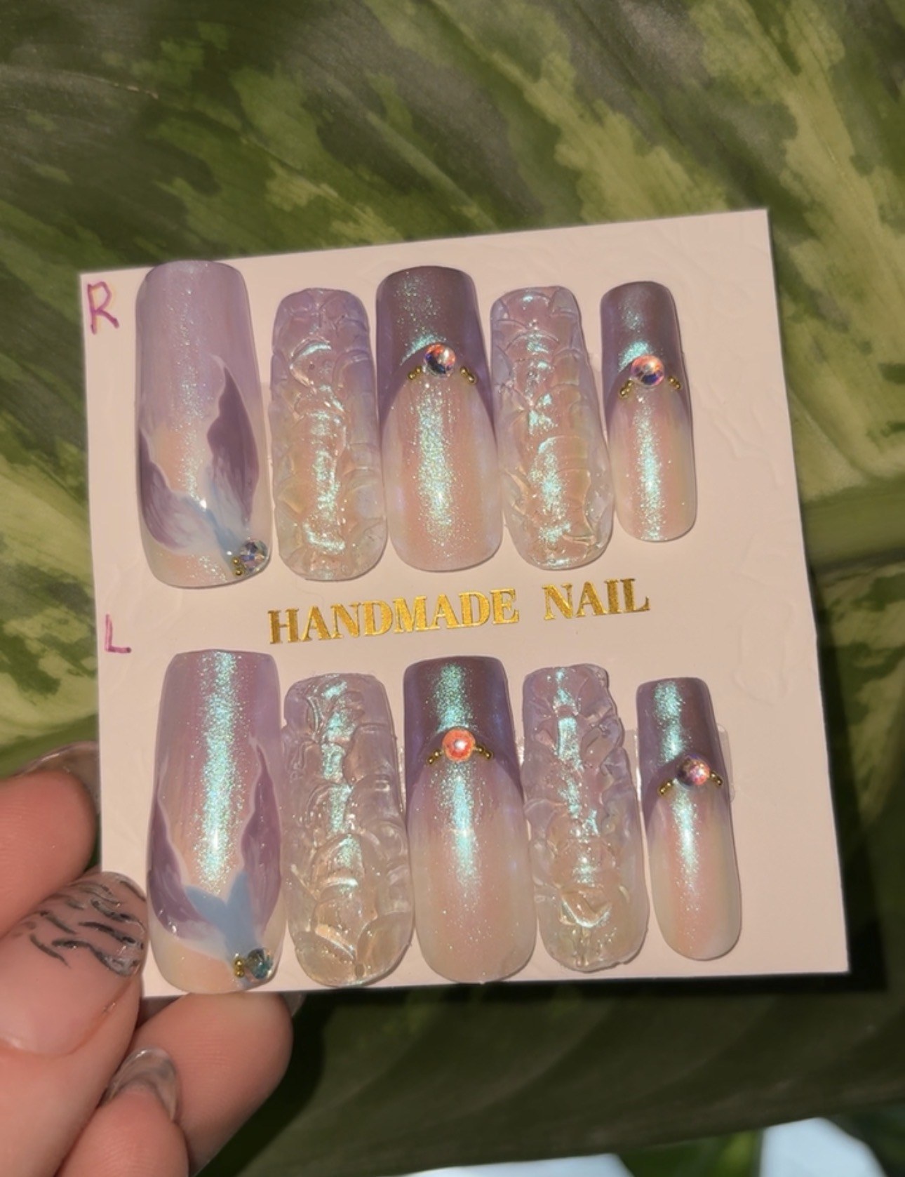 Purple and iridescent press-on nails with sculpted texture and gem accents