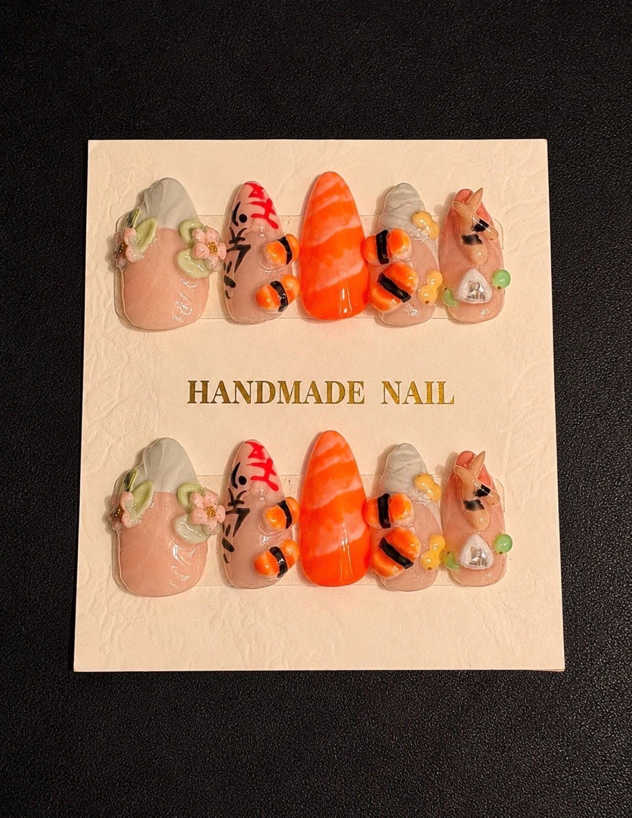 Handcrafted nails with miniature sushi, orange salmon stripes, flowers and food details